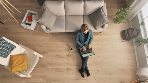 businesswoman sitting on floor works from home using computer top down view overhead,young business woman freelancer working remote typing on laptop above shot indoors,distance work concept