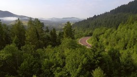 Drone flies over a winding road that passes through a mountains. Location place Carpathian mountains, Ukraine, Europe. Cinematic aerial shot. Discover the beauty of earth. Filmed in 4k, drone video.