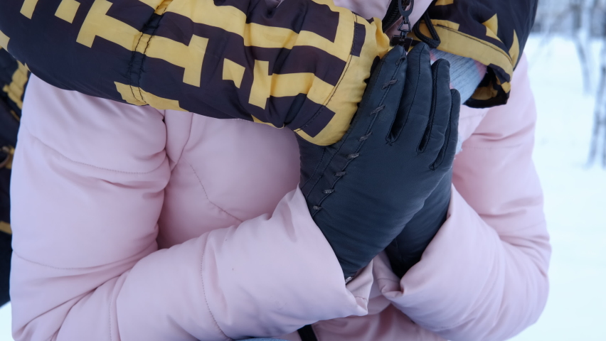 Winter moments with family. A view of a happy mother and smiling daughter embraing on the white snowing landscape.
