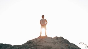 4k video. A man stands on a high mountain facing the sun and victoriously opens his hands. The concept of tourism and hiking