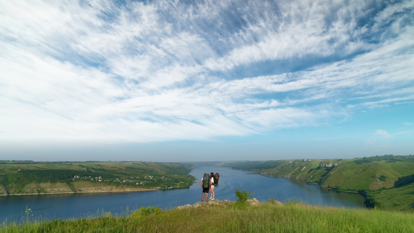 The couple of tourists standing on the mountain top above scenic river