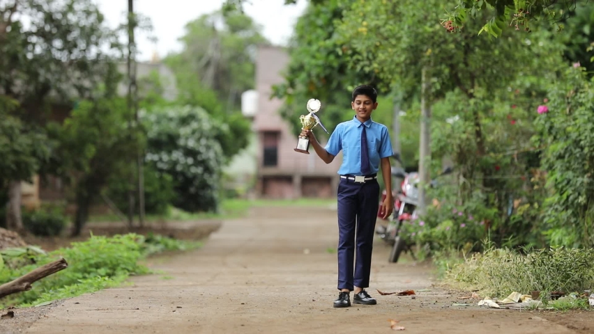 Clever schoolboy raising his trophy as a winner in school competition. Royalty-Free Stock Footage #1079274920