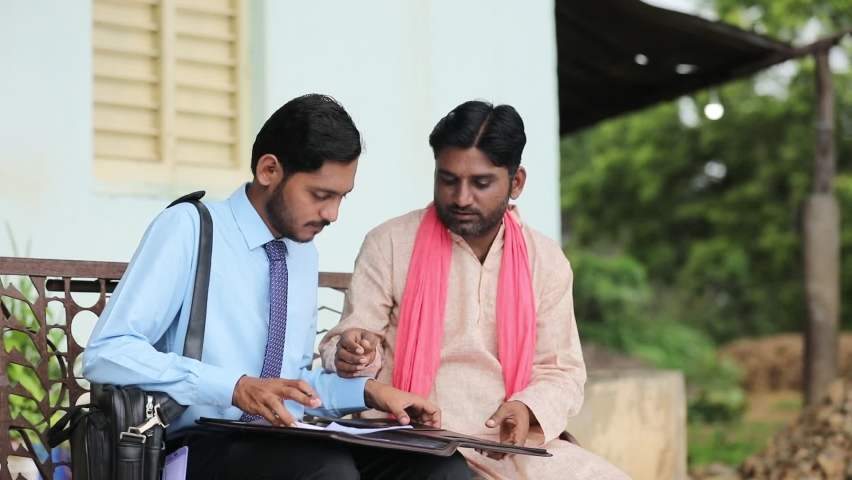 young india bank officer completing paper work with farmer.