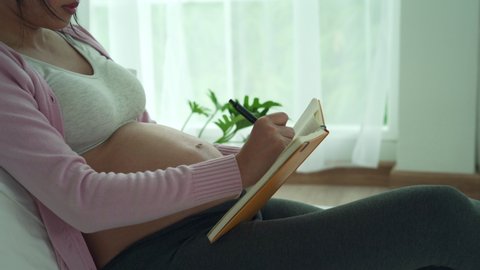 preparing for mother. A pregnant woman write down on book about equipment for newborn. Caesarean section is a way for pregnant women to know a due date.