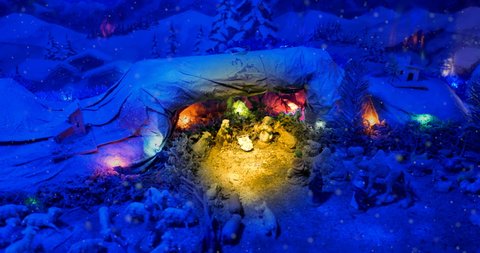 Christmas Nativity Scene with hand-coloured figures in a winter landscape. A magical night atmosphere with colored lights and falling snow.