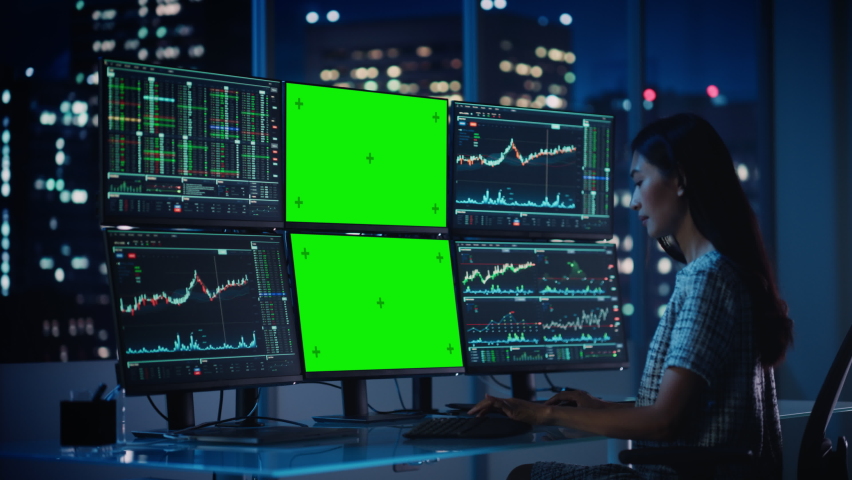 Financial Analyst Working on Computer with Multi-Monitor Workstation with Green Screen Chroma Key Mock Up Template and Real-Time Stock Charts. Businesswoman Works in Investment Bank in the Evening. Royalty-Free Stock Footage #1079285207