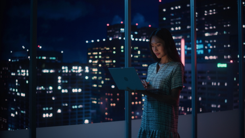 Financial Analyst Using Laptop Computer, Standing Next to Window with Beautiful Night City Skyline with Skyscrapers. Confident Asian Businesswoman Working in Modern Corporate Office. | Shutterstock HD Video #1079285354