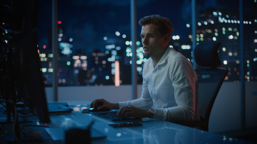 Financial Analyst Working on a Computer with Multi-Monitor Workstation with Real-Time Stocks, Commodities and Exchange Market Charts. Businessman Works in Investment Bank Downtown Office at Night. | Shutterstock HD Video #1079285363