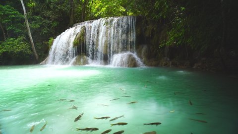 Waterfalls and fish swim in the emerald blue water in Erawan National Park. Erawan Waterfall is a beautiful natural rock waterfall in Kanchanaburi, Thailand.Onsen atmosphere. soft focus.