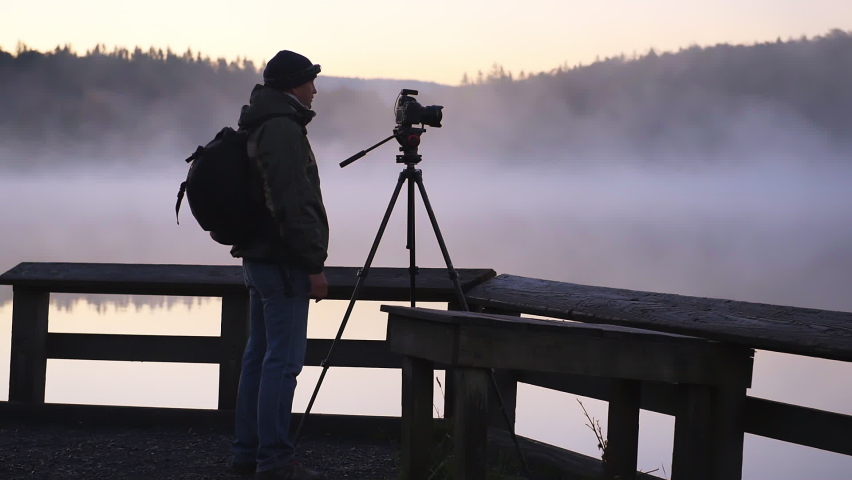 Spruce Knob Lake in West Virginia at sunrise with photographer man with tripod camera and landscape view of fog mist water and forest trees with sunlight