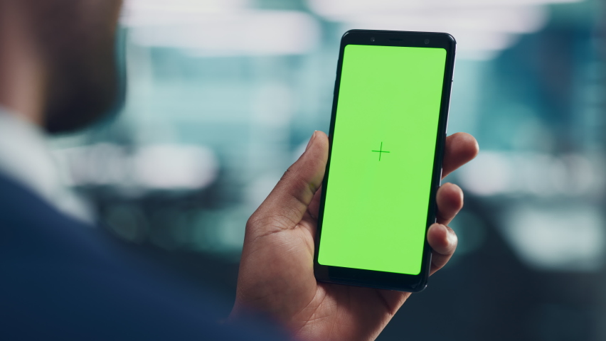 Black Man with Green Screen Chroma Key Smartphone in Office. African-American Person using Internet, Social Media, Online Shopping with Mobile Phone Device. Focus on Display, Hand Royalty-Free Stock Footage #1079293124