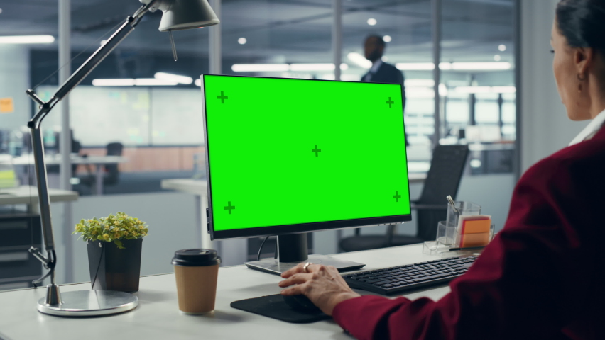 Successful Caucasian Businesswoman Sitting at Desk Working on Green Screen Laptop Computer in Office. Beautiful Businessperson using Chroma Key Display. Over Shoulder Royalty-Free Stock Footage #1079293133