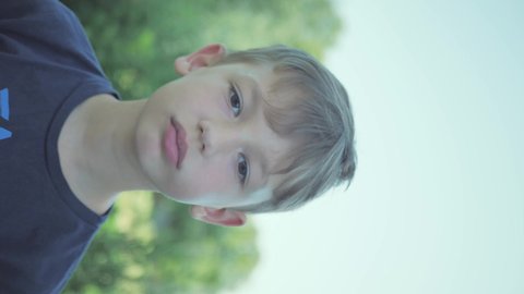 boy chews an apple in nature. vertical video