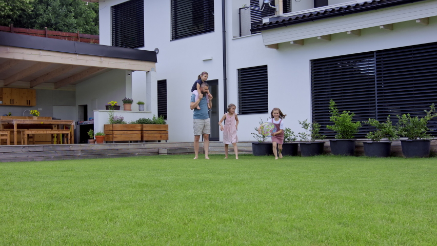 Father with daughters playing outdoors in the backyard, running.