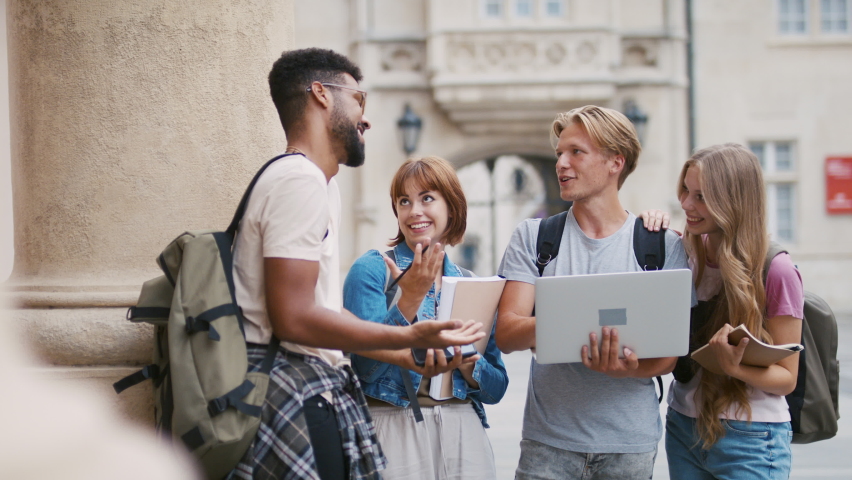 Group of students meeting in front of the university building, talking about school project.