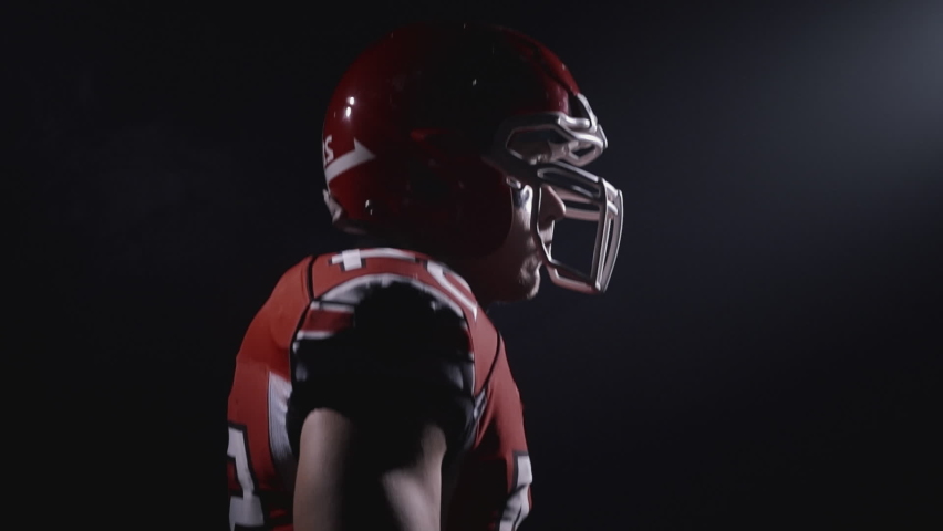 Profile portrait of determined professional American football player in helmet ready for game and attack. Confident and agressive man in uniform. Usa team game and extreme sport spirit concept.