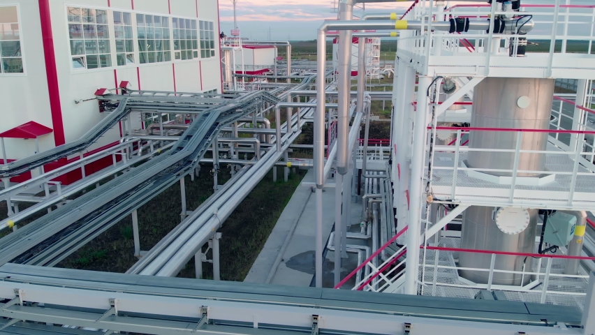 A drone at an oil refinery flies around tanks for storing and cleaning oil and gas. Oil and gas industry and work with natural gas. The worker makes a check, climbs the stairs to the gas storage. Royalty-Free Stock Footage #1079307950