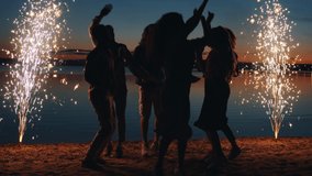 Happy youth girls and guys are having fun on beach at night dancing and enjoying fireworks celebrating festive event. People and outdoor joy concept. - Powered by Shutterstock - Get 15% off with code: PIKWIZARD15