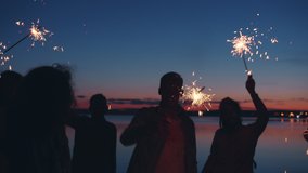 Slow motion of human silhouettes dancing at night beach party waving bengal lights enjoying event having fun together. People and emotions concept. - Powered by Shutterstock - Get 15% off with code: PIKWIZARD15