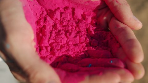 Close-up of hands holding pink gulal colored powder for Holi festival ready for celebration outdoors on summer day. Ceremonies and fun concept.