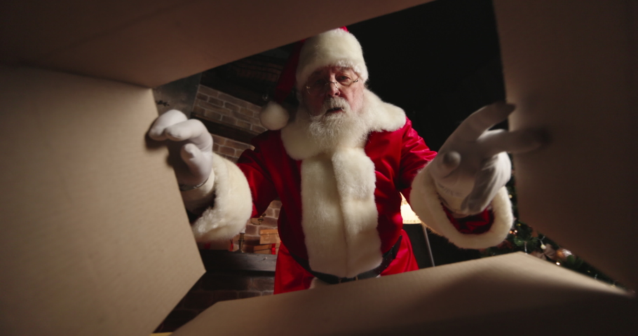 Christmas eve. Funny Santa Claus Packing Present Looking Inside Cardboard Box Wrapping Toy Plane Gift Preparing Package Delivery on Xmas eve. Merry Christmas Surprise Concept, Close up View from Below