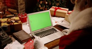Bearded Santa Claus having a video chat using laptop computer with green chroma key screen. St Nicholas talking to kids on web - christmas spirit magic, technology 4k footage
