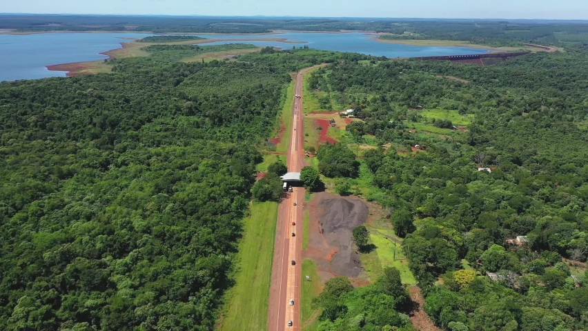 Incredible exotic road crossing a jungle and a large lake in Misiones, Argentina. Drone view seen from above.