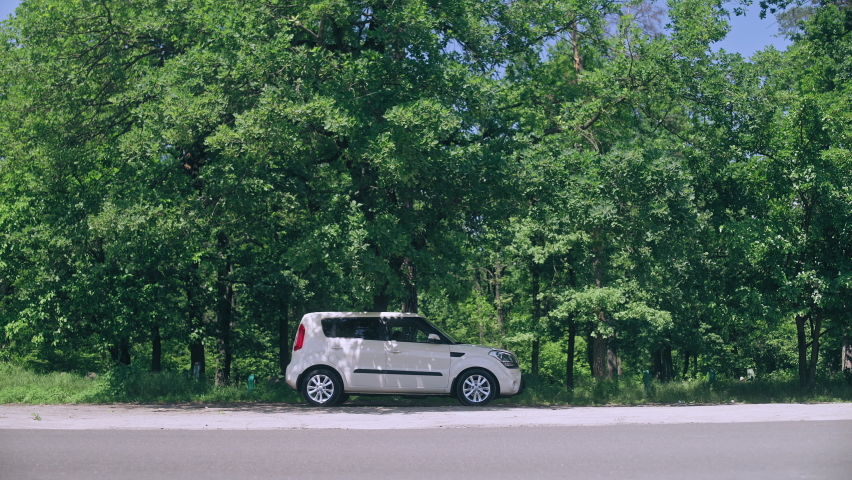 Confused woman opening hood of the car on the roadside, stalled automobile