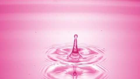 Drop of water falls down on pink clear fluid surface creating concentric circles on it on pale pink background | Abstract skin moisturizing cosmetics formulating concept