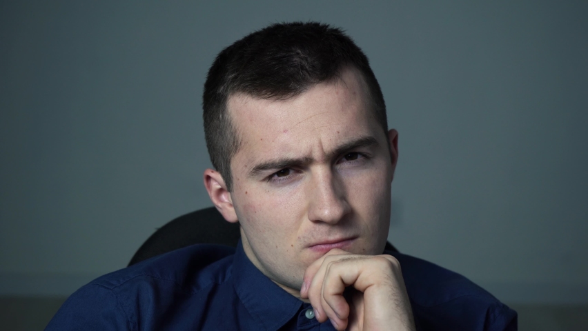 stern male director sits at the table and looks at the camera