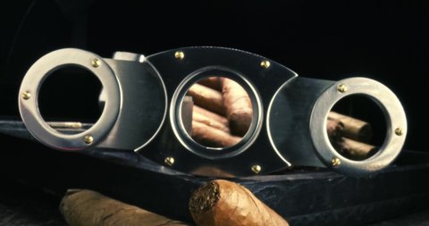 View through a cigar cutter. Cigars in humidor with lighter. Cigars, lighter and cutter in humidor. Parallax effect.