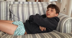 Young boy watching movie lying on couch at night staring at TV screen