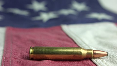 Brass Bullet Of A Rifle-Caliber Laid On American Flag Fabric. close up, slider shot