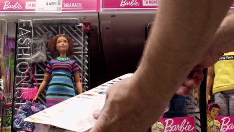 Lviv, Ukraine - June 9, 2021: The buyer in the toy store chooses a Barbie doll.