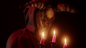 Devil with cow skull head holding burning candles. Demon with horns conjuring close-up. Evil imp wearing black robe with hood using witchcraft in darkness. Halloween and full moon. - Powered by Shutterstock - Get 15% off with code: PIKWIZARD15