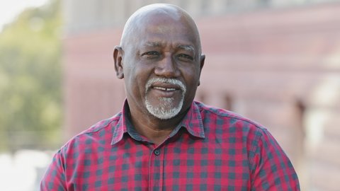Closeup portrait of handsome face of elderly black man with smile. Friendly mature bearded African American male in shirt looking at camera. Concept of healthy person enjoying retirement life