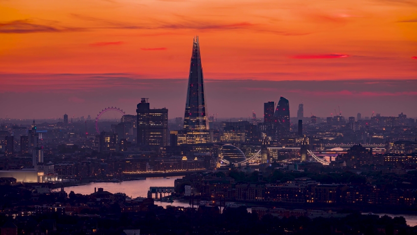 Sunset to night time lapse view of the skyline of London, United Kingdom, with Tower Bridge and the modern office skyscrapers along the Thames river