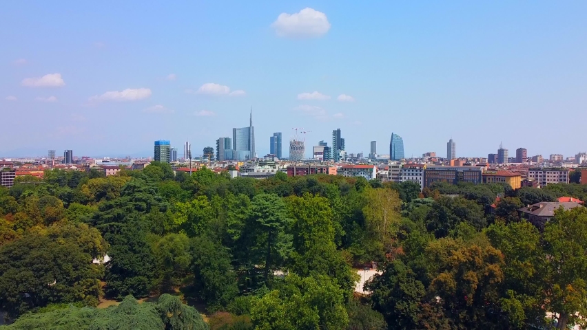 Aerial view of autumn trees in sempione park next to castello sforzesco castle. City and roofs of buildings. View of modern skyscrapers. Ecology. Green Planet. Skyline. Milan. Italy,  Royalty-Free Stock Footage #1079350778