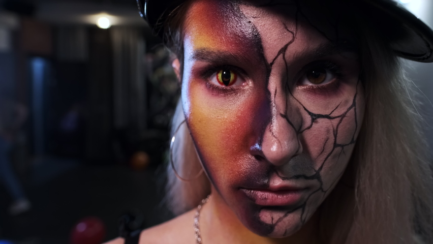model in black cap on dark background posing makeup on face holiday Halloween close-up slow motion