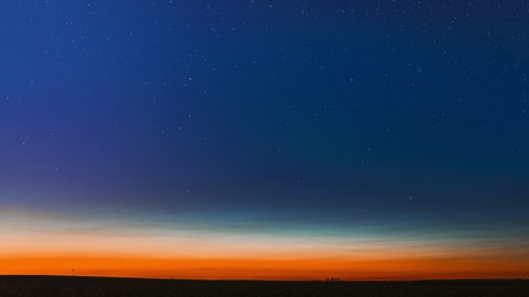 Night Starry Sky With Glowing Stars Above Countryside Field Landscape In Early Spring. Bright Glow Of Planet Venus In Sky Among The Milky Way Galaxy Stars. Sky In Lights Of Sunset Dawn. 4K Timelapse.