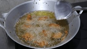 HD video of closeup chicken pieces frying in a hot boiling oil. Top view of unhealthy oily food being prepared at home in the kitchen. 