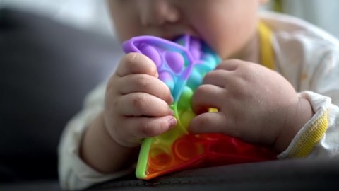 Close up the hand of little baby boy chew rainbow sensory toy