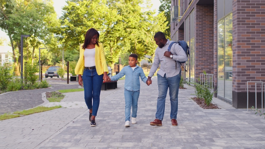 Young handsome mom and dad take their son to school. Beautiful family talk to each other. Royalty-Free Stock Footage #1079371151