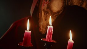 Devil with cow skull head making rite, holding burning candles. Demon with horns conjuring close-up. Evil imp wearing black robe with hood using witchcraft in darkness. Halloween and full moon. - Powered by Shutterstock - Get 15% off with code: PIKWIZARD15