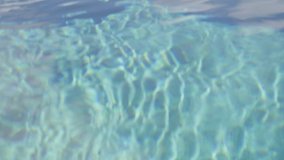 Pure blue water in the pool with light reflections. Slow motion. The texture of water with reflections and sunbeams, a wonderful natural color of the sea wave Close-up in slow motion, meditative video