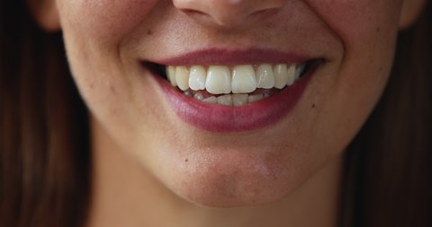 Cropped view lower part of pretty young woman face speaking talking before camera showing white straight healthy teeth. Close up of beautiful female lips smiling and moving when lady is making speech