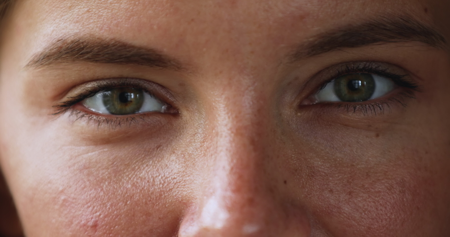 Gaze. Beautiful green eyes of young smiling female looking at camera. Macro view of attractive millennial woman happy face with opened eyes thick eyebrows cute freckles on smooth skin. Cropped closeup Royalty-Free Stock Footage #1079380532