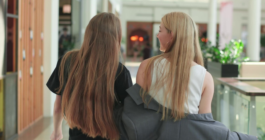 Stylish friends are walking in the mall, laugh and hugging. Happy friends go home after succesful shopping. 4K video
