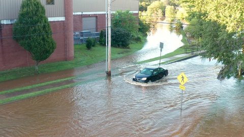 Manheim , PA , United States - 09 01 2021: Car driving through flood waters on street. Turn around, don't drown. Aerial view. Hurricane rainfall.