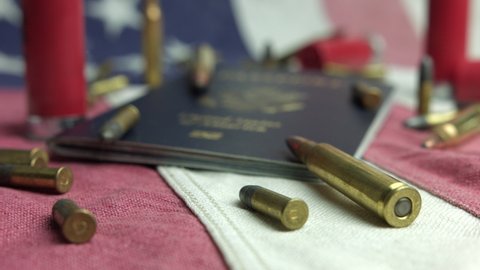 Elmira , New York , United States - 09 16 2021: Caliber Bullets, Shotgun Shells, And American Passport On Patriotic American Flag. close up, tilt-up